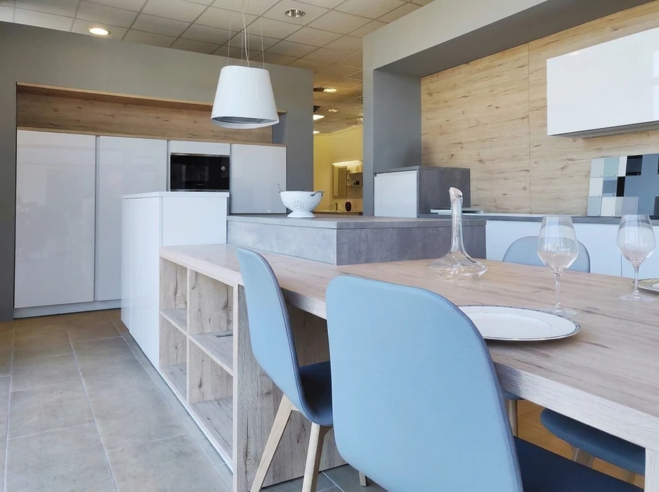 Cuisine moderne ouverte avec îlot central en béton ciré gris, table en bois clair avec chaises scandinaves bleues