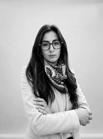 Photographie d'un professionnel cuisiniste en consultation avec un couple de clients dans un showroom haut de gamme. Le professionnel, en tenue professionnelle, pointe du doigt vers une cuisine modèle ou un plan 3D sur écran/tablette, expliquant le projet. Les clients l'écoutent attentivement, souriants et engagés. L'environnement du showroom est visible en arrière-plan (cuisine aménagée, éclairage professionnel, atmosphère chaleureuse et accueillante). La scène capture la relation de confiance, l'écoute et le caractère sur-mesure de l'accompagnement.