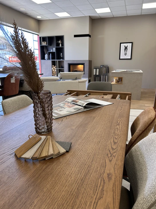 Cuisine moderne ouverte avec îlot central en béton ciré gris, table en bois clair avec chaises scandinaves bleues